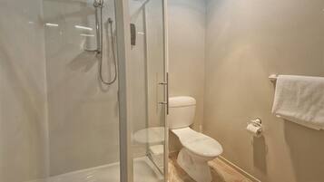 A bathroom with a glass-enclosed shower, a toilet, and a towel rack.