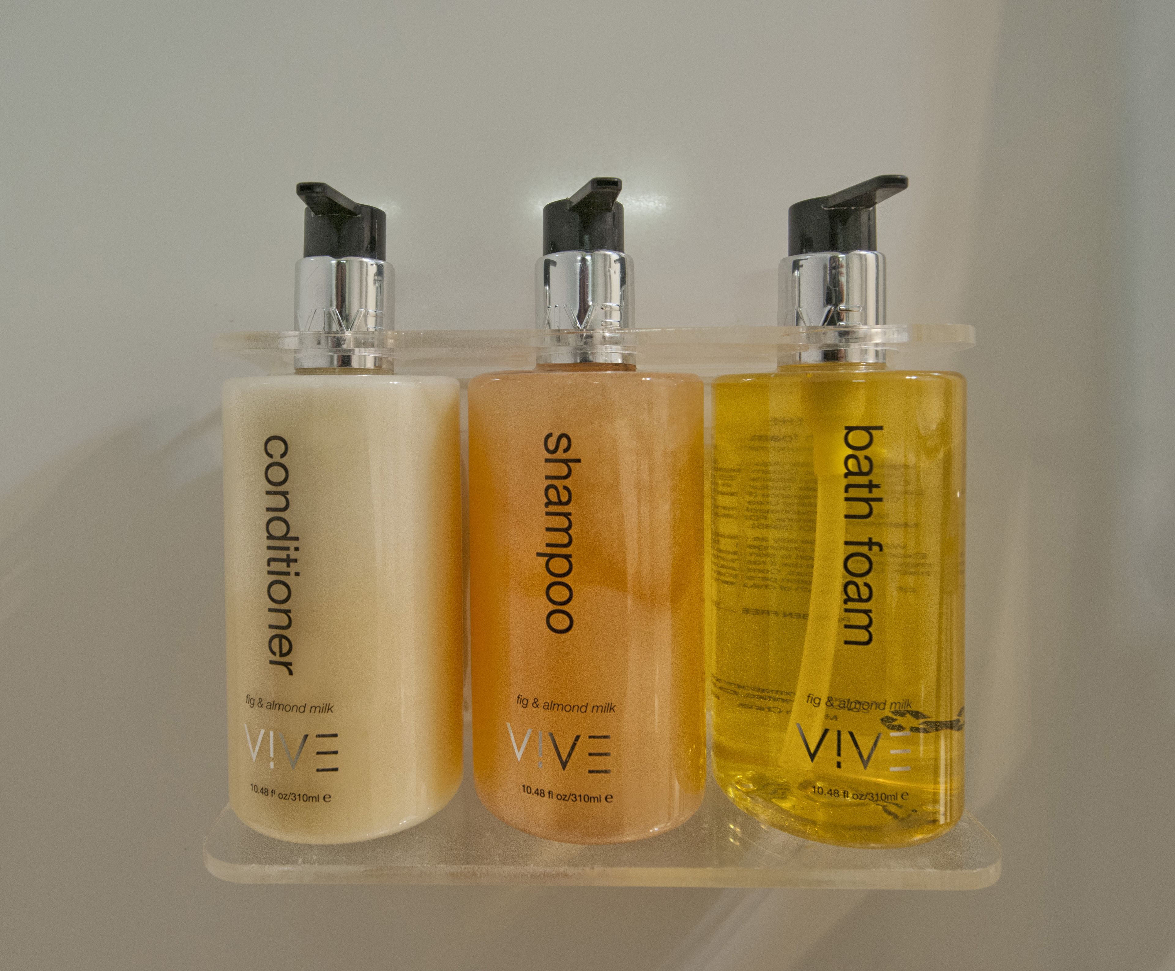 Three bottles of VIVE skincare products on a clear shelf.