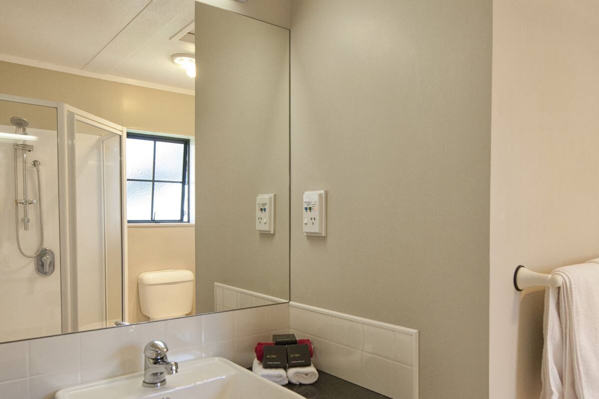 A bathroom with a white sink, a mirror, a towel rack, and a shower.
