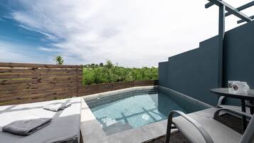 Área de piscina no terraço com deck de madeira, uma pequena mesa com duas canecas brancas e um banco com toalhas.