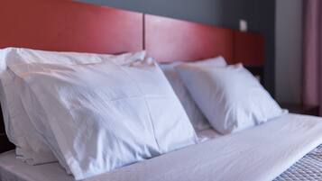A bed with white bedding and a red headboard in a hotel room.