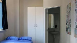 A bedroom with a bed, a wardrobe, and a bathroom visible through an open door.