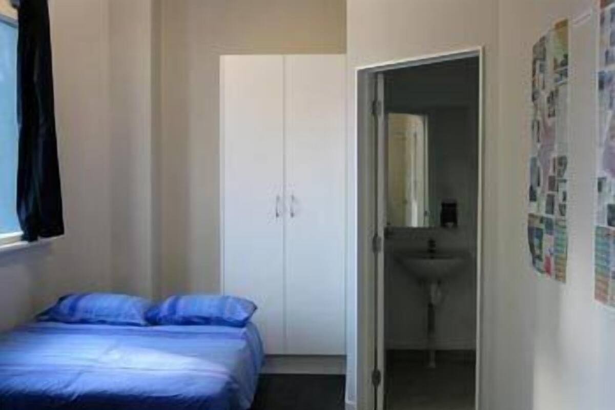 Une chambre à coucher avec un lit, une armoire et une salle de bain visible à travers une porte ouverte.