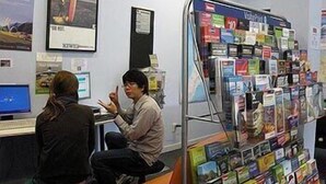A bookstore with a variety of books on display and a computer monitor on the counter.