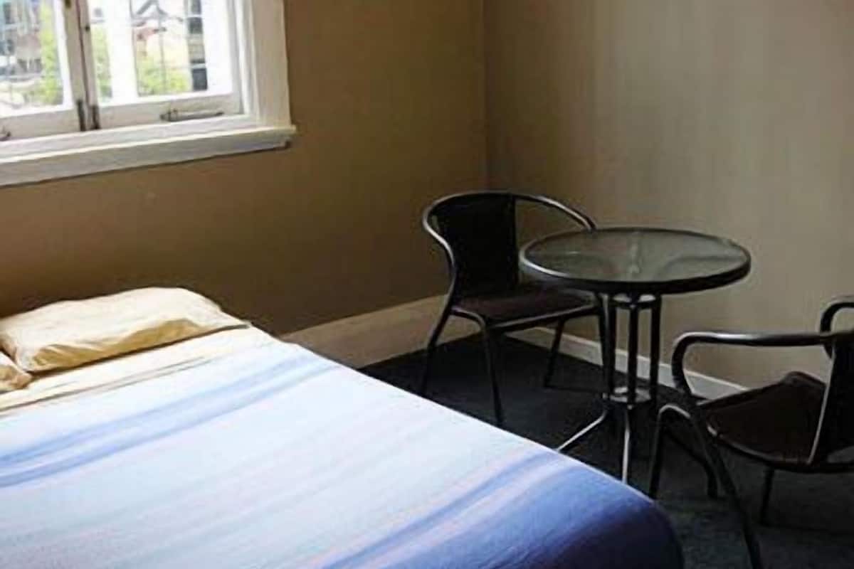 Une pièce comprenant un lit, une petite table ronde et deux chaises.