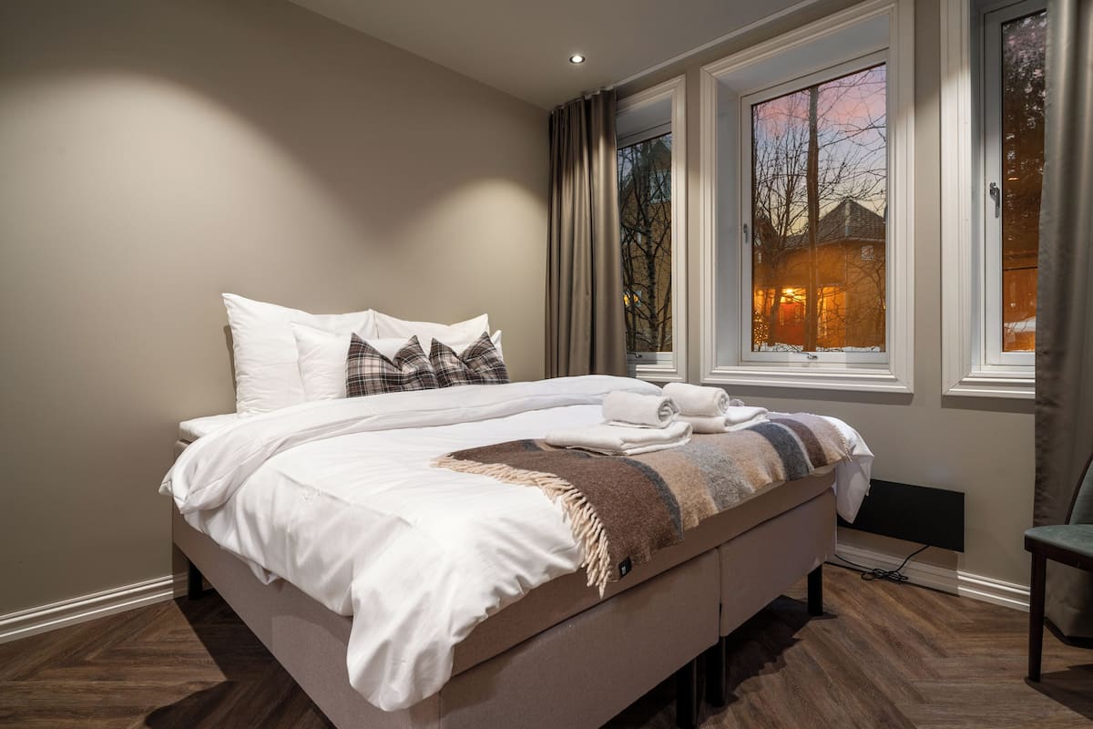 Een moderne hotelkamer met een groot bed, uitzicht door een raam en een stoel bij het raam.