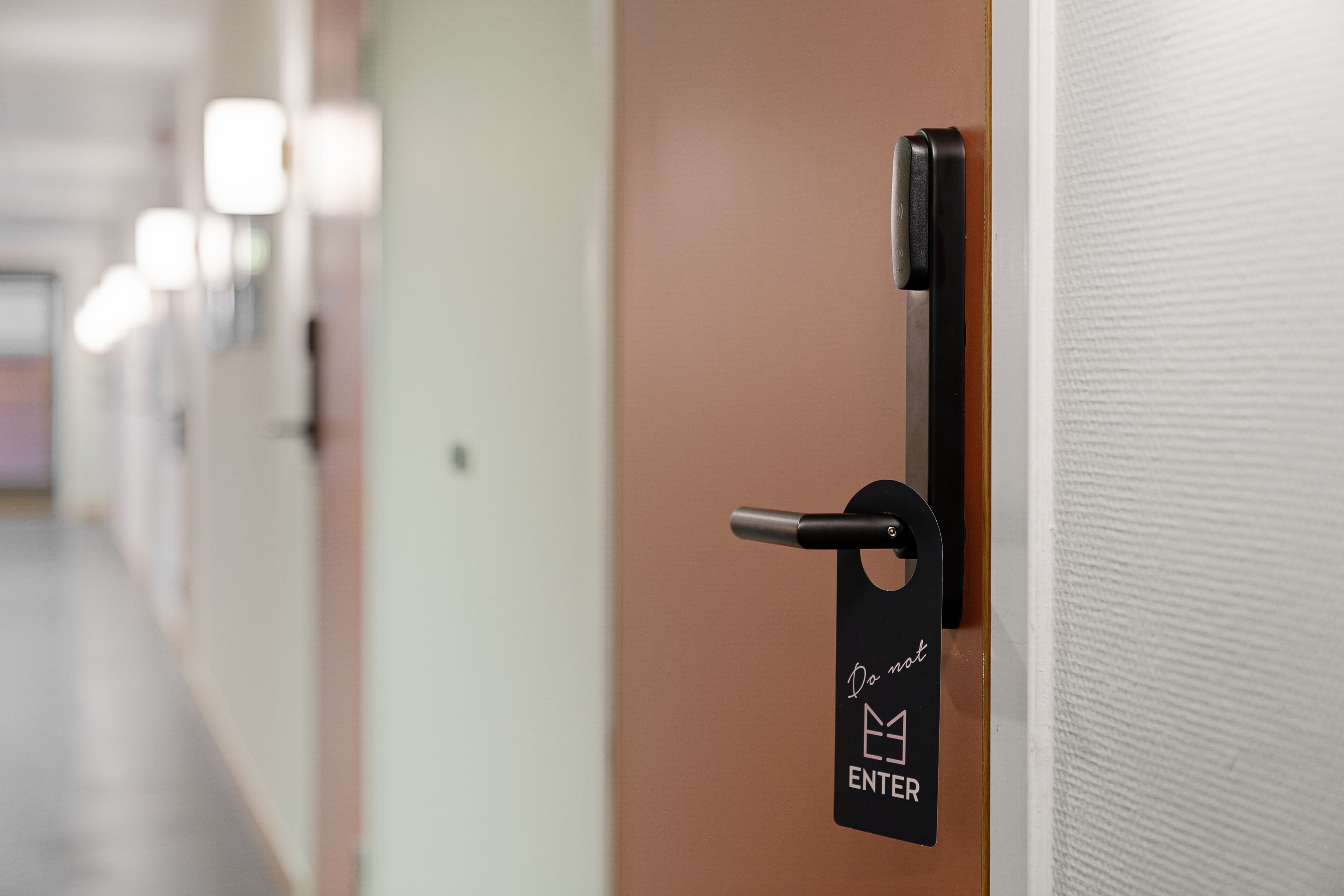 A hotel room door with a black handle and a sign that reads "Do not enter."