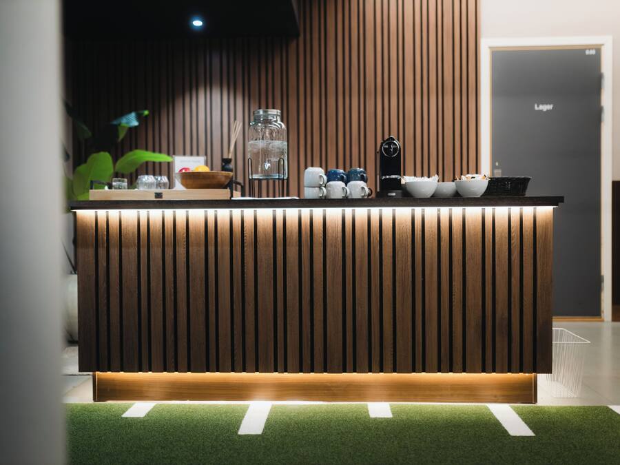 Una recepción con mostrador de madera, un tarro de vidrio y una máquina de café negra.