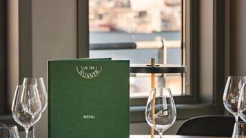 A dining table with a menu book, wine glasses, and a napkin.