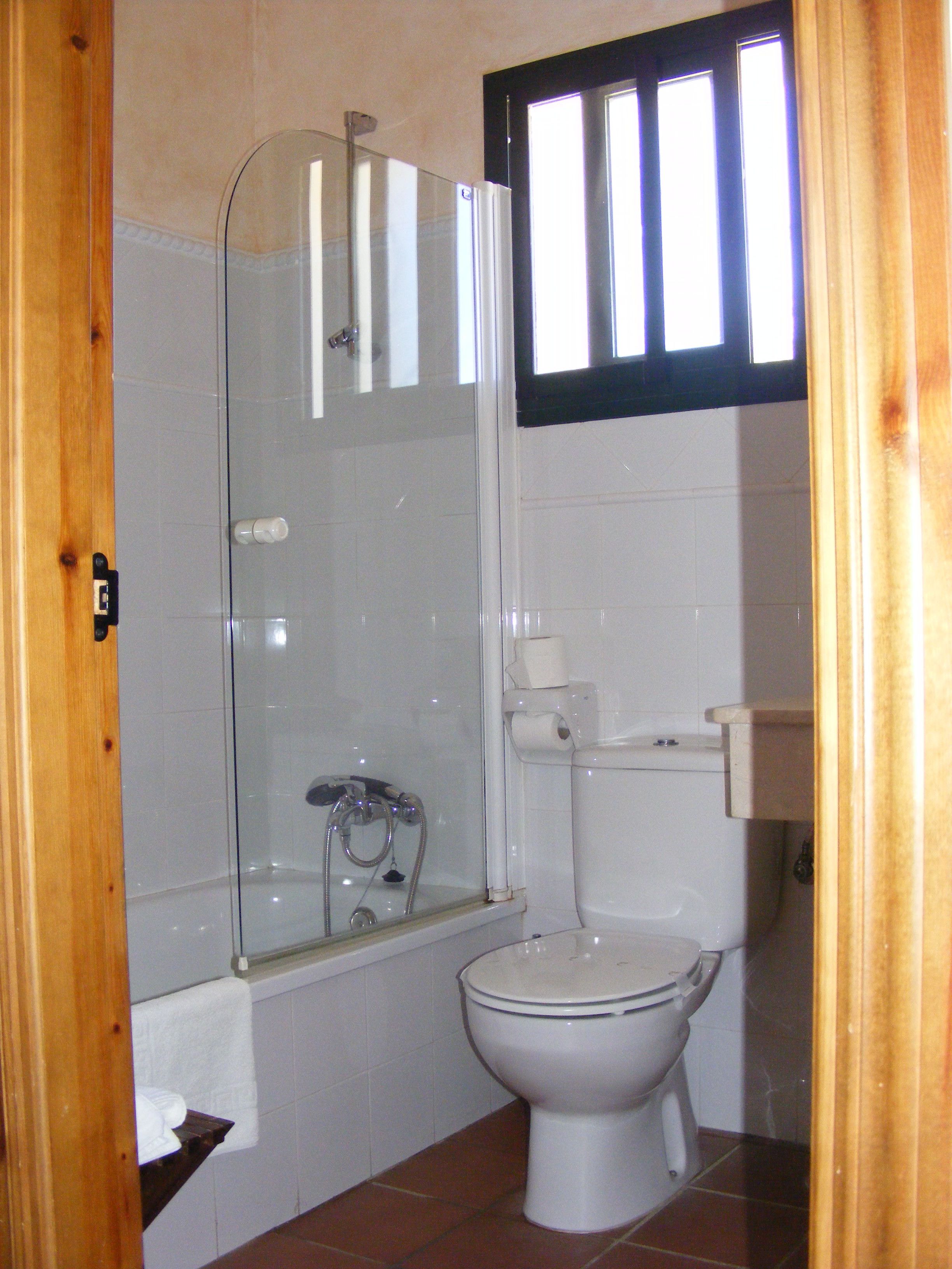 A bathroom with a glass shower enclosure, a toilet, and a sink.