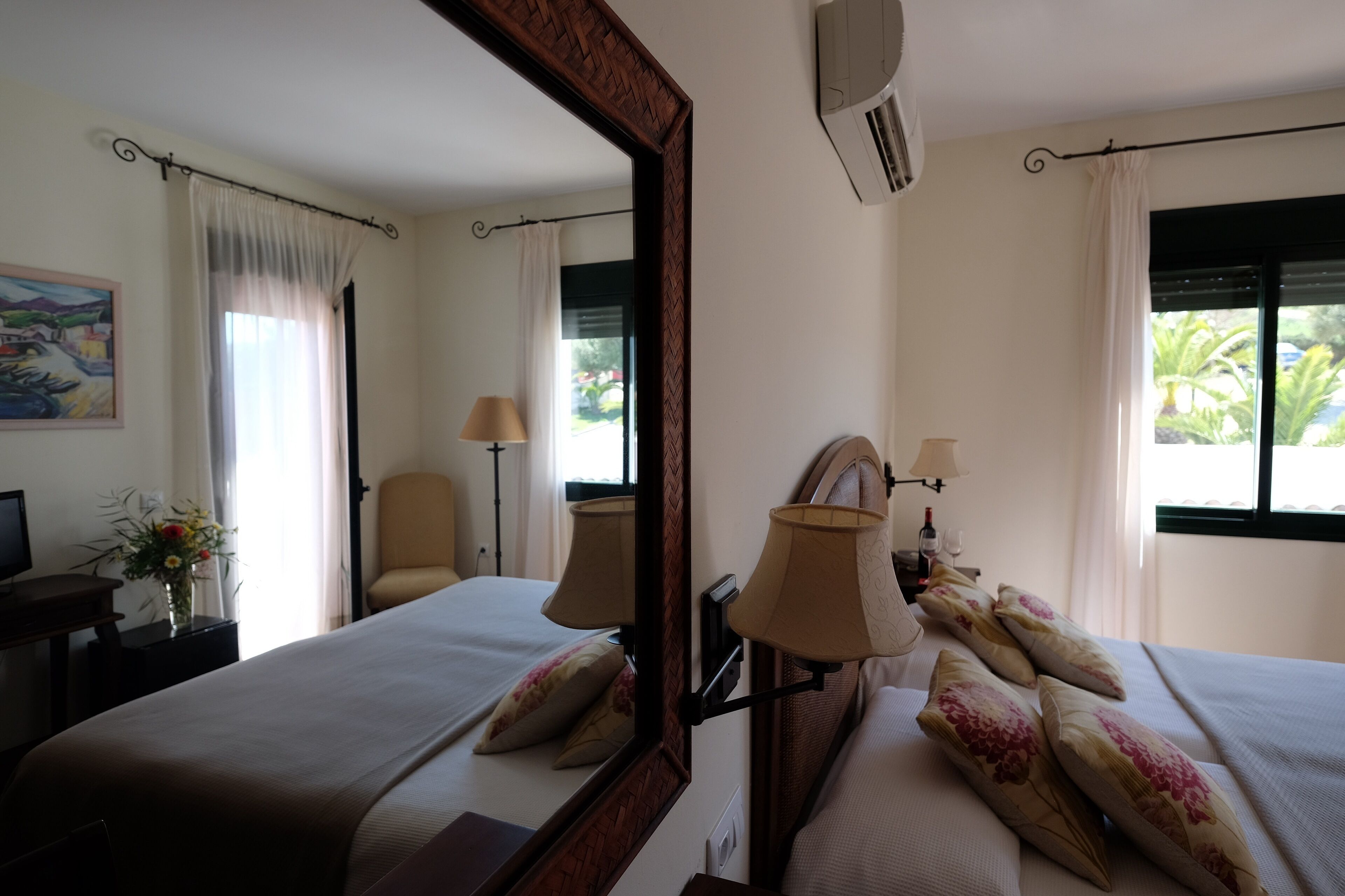A hotel room with a large bed, two bedside lamps, a chair, a desk, and a mirror.