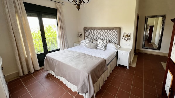 Un dormitorio con cama, mesitas de noche, un espejo y una ventana con cortinas.