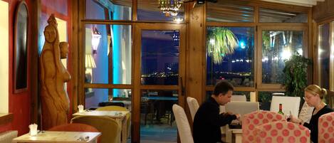 A restaurant with wooden walls, large windows, and a view of the city at night.