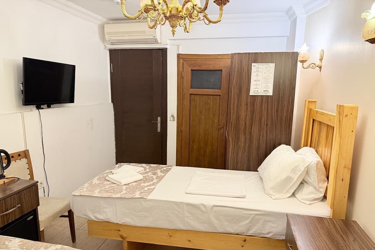A bedroom with a wooden bed, a television, a desk, and a chair.