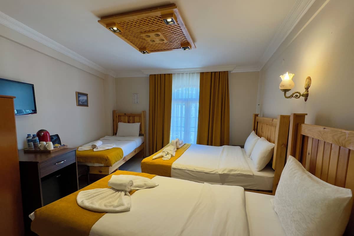 A hotel room with two beds, a desk with a coffee maker, and a TV.