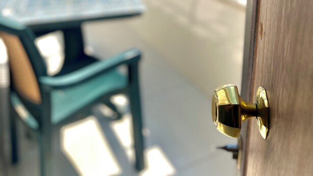A rooftop terrace with a table and chairs, a door with a brass handle, and a view of buildings in the background. - Magnificent Hotel (Istanbul)