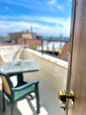 A rooftop terrace with a table and chairs, a door with a brass handle, and a view of buildings in the background. - Magnificent Hotel (Istanbul)