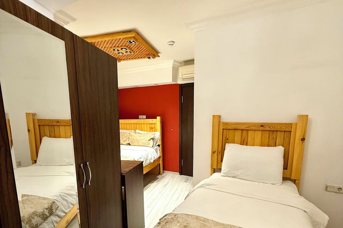 A bedroom with two beds, a wardrobe, and a ceiling with a decorative pattern.