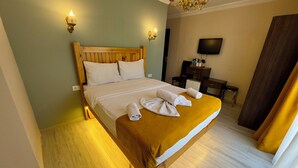 A hotel room with a wooden bed, a desk, a television, and a chandelier. - Magnificent Hotel (Istanbul)