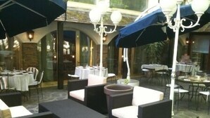 An outdoor dining area with wicker furniture, umbrellas, and chandeliers. - Inter-hotel Au Pavillon Bleu (Ozoir-la-Ferriere)