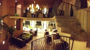 A hotel lobby with a staircase, seating area, and a view of the outdoor space. - Inter-hotel Au Pavillon Bleu (Ozoir-la-Ferriere)