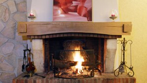 A fireplace with a stone mantle, a framed artwork above it, and two candles on either side. - Inter-hotel Au Pavillon Bleu (Ozoir-la-Ferriere)