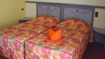 A double bed with a floral bedspread and an orange bag on it.