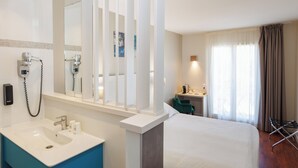 A hotel room with a bed, a bathroom with a sink and mirror, a desk with a chair, and a window with curtains. - The Originals Boutique, Hôtel Cassitel, Cassis Port (Cassis)