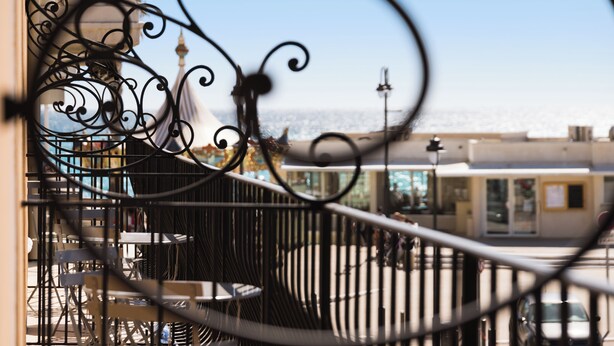 A balcony with a wrought iron railing, overlooking a cityscape and a body of water. - The Originals Boutique, Hôtel Cassitel, Cassis Port (Cassis)
