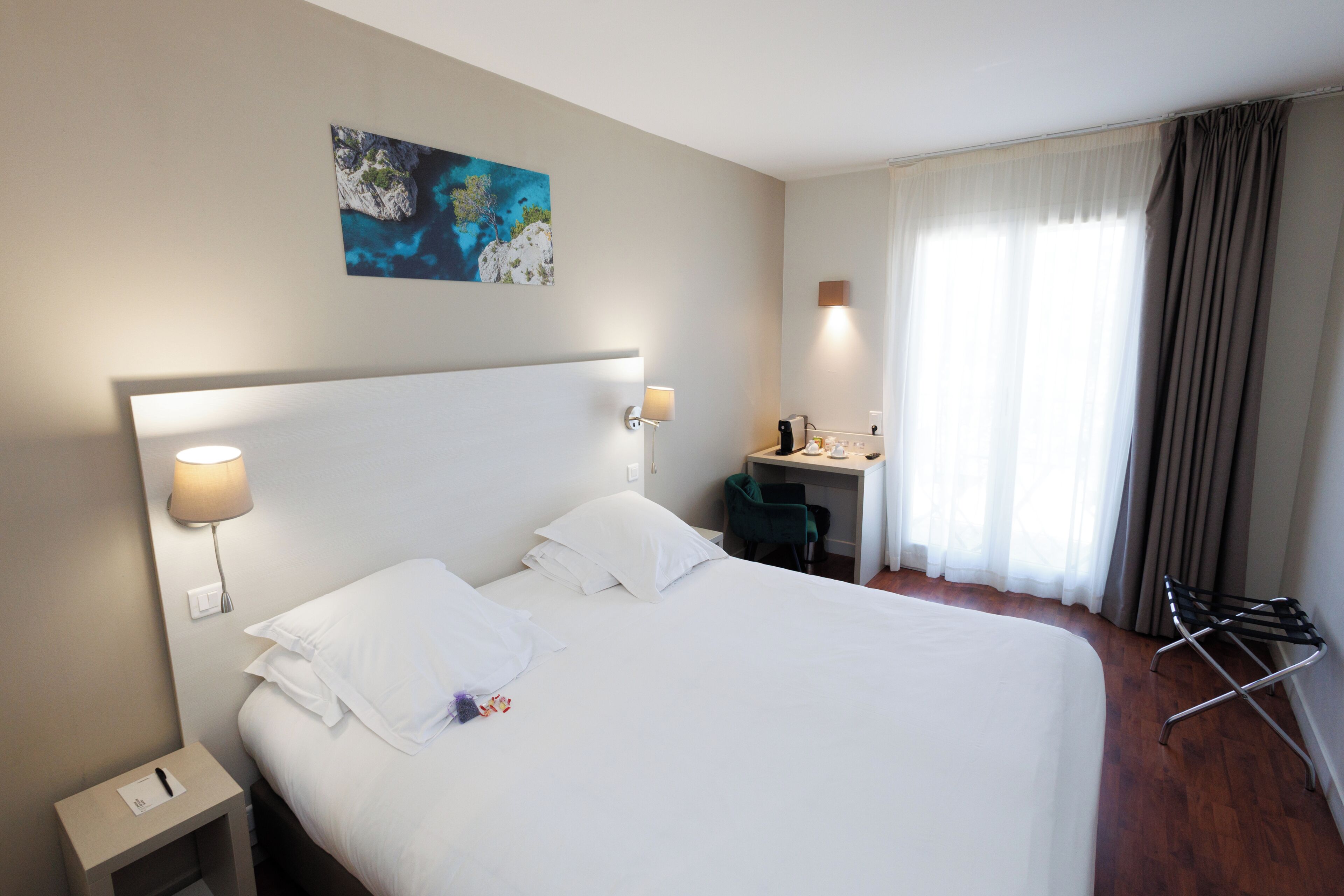 A hotel room with a large bed, bedside lamps, a desk, and a window with curtains.