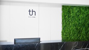 A reception desk with a logo, a green wall, and a marble counter. - Telioni (Thessaloniki)