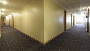 A long, narrow hotel corridor with carpeted floors and cream-colored walls. - Telioni (Thessaloniki)