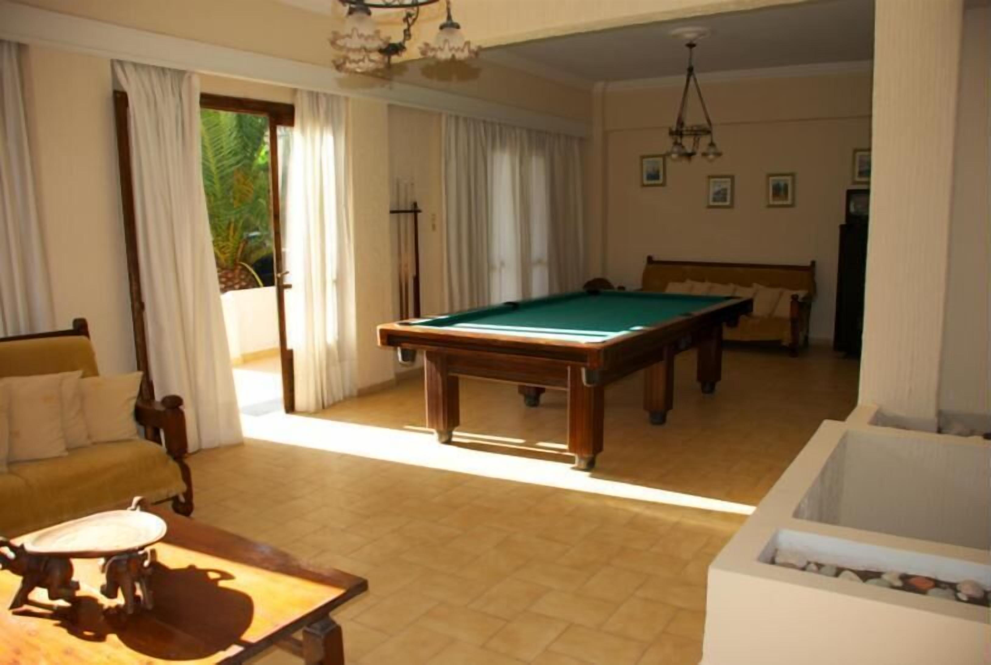 A room with a pool table, a sofa, and a billiard cue rack.
