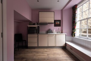 Cocina compacta con horno integrado, microondas y lavabo.