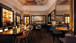 Un espace bar doté d’un comptoir en marbre, de tabourets de bar et d’un grand tableau accroché au mur.
