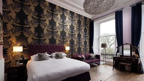 Une chambre à coucher avec un grand lit, un canapé, une commode et une fenêtre avec des rideaux.