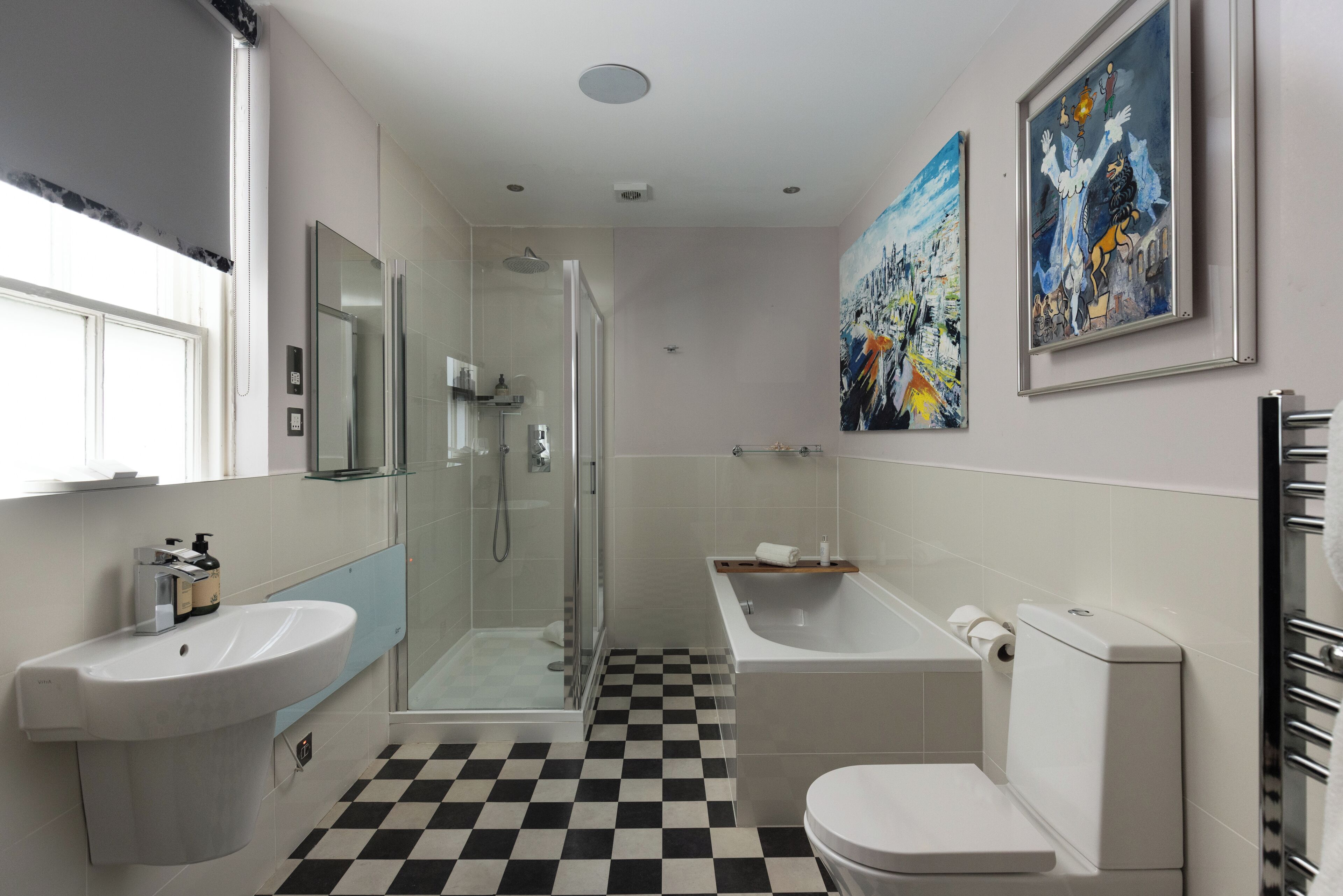 A modern bathroom with a checkered floor, a glass shower enclosure, a freestanding bathtub, and a toilet.