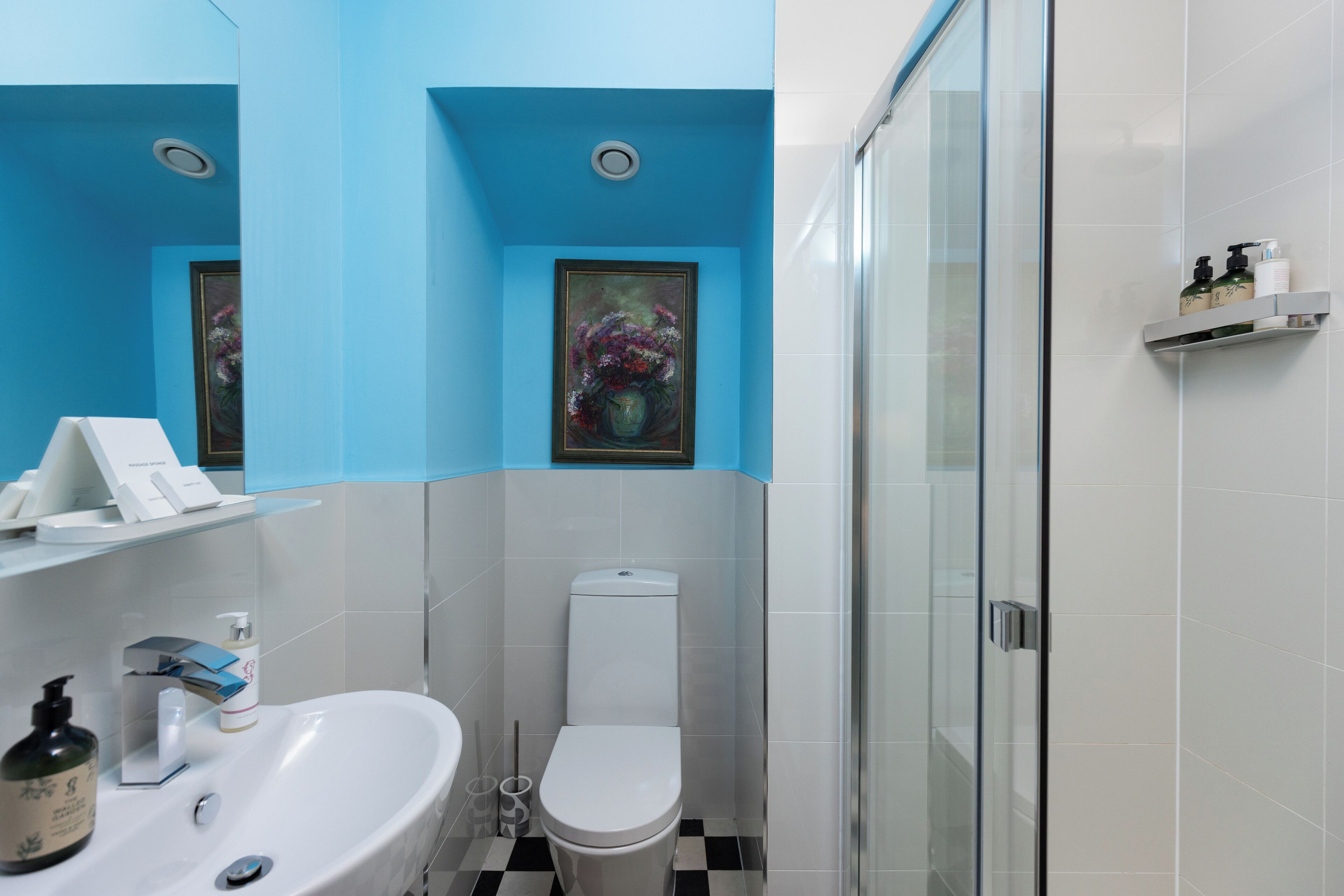 Une salle de bain avec un lavabo blanc, des toilettes et une douche à parois de verre.