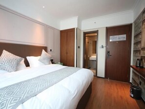 Een hotelkamer met een groot bed, een houten garderobe en een kleine kitchenette.