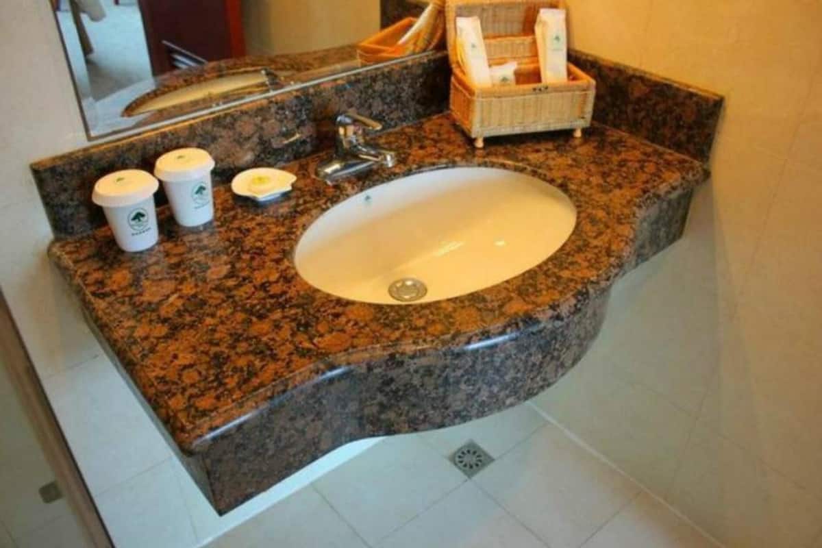 A bathroom with a granite countertop, a sink, and a mirror.