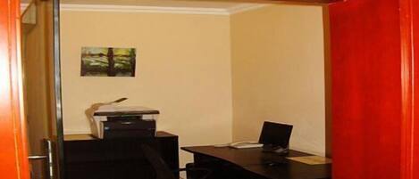 Una habitación con un escritorio, una silla y una puerta con marco rojo.