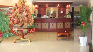 A hotel reception area with a large floral arrangement, a reception desk, and a receptionist. - Green Tree Inn Zhenjiang Zhongyang Street RT-MART (Zhenjiang)