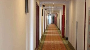 A long, narrow hallway with a patterned carpet, red and white doors, and a ceiling with recessed lighting. - Green Tree Inn Zhenjiang Zhongyang Street RT-MART (Zhenjiang)