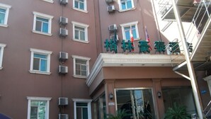 A hotel building with multiple air conditioning units, a flag, and a sign in a foreign language. - Green Tree Inn Zhenjiang Zhongyang Street RT-MART (Zhenjiang)