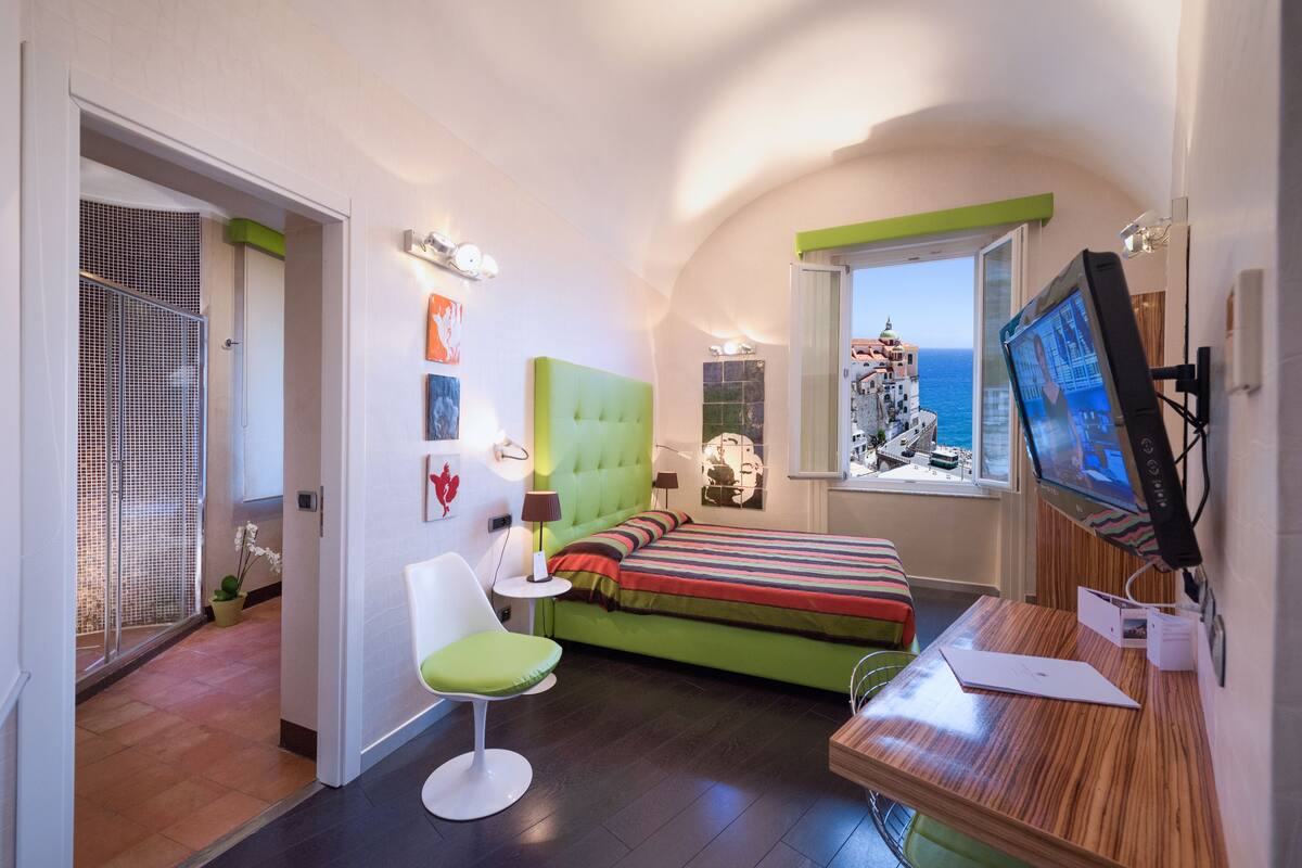 Una habitación pequeña con cama, escritorio, silla y televisor.
