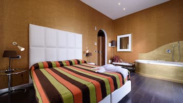 Quarto de hotel moderno com uma cama grande, banheiro privativo com banheira e uma pequena área de estar.