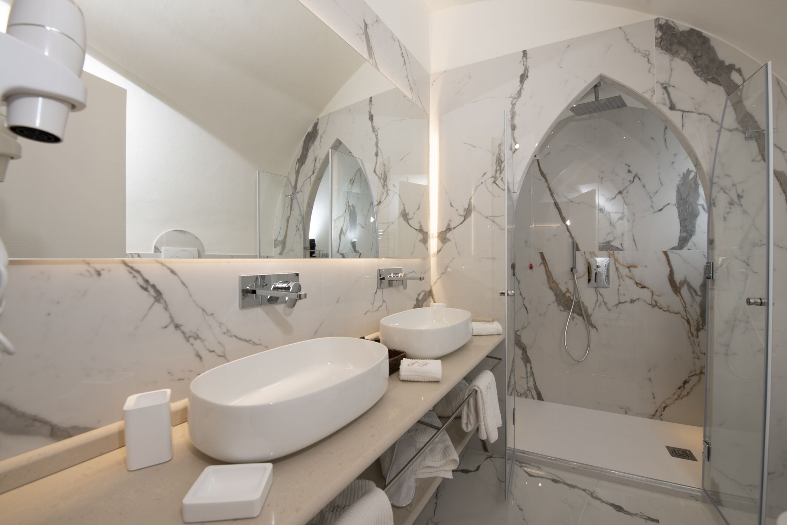Un baño moderno con dos lavamanos, ducha y un espejo grande.