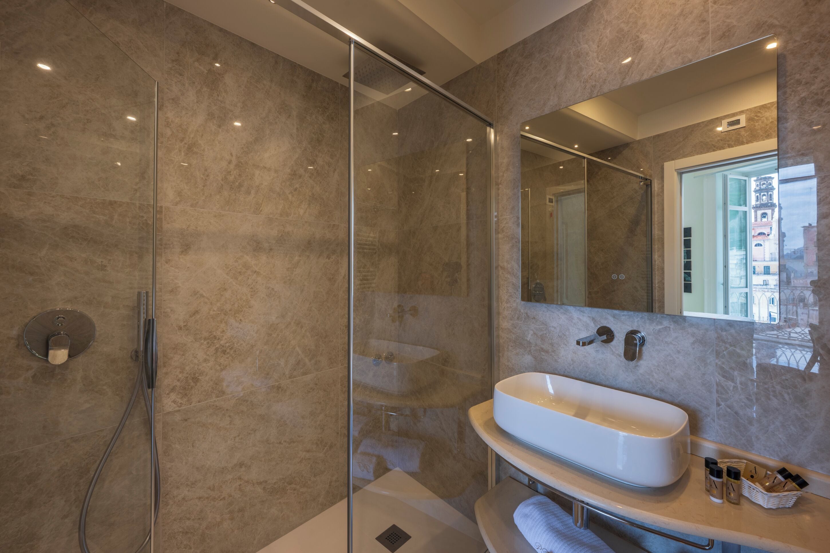 A modern bathroom with a glass shower enclosure, a freestanding bathtub, and a large mirror.