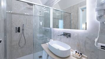 Un bagno moderno con doccia vetro, lavandino bianco e specchio.