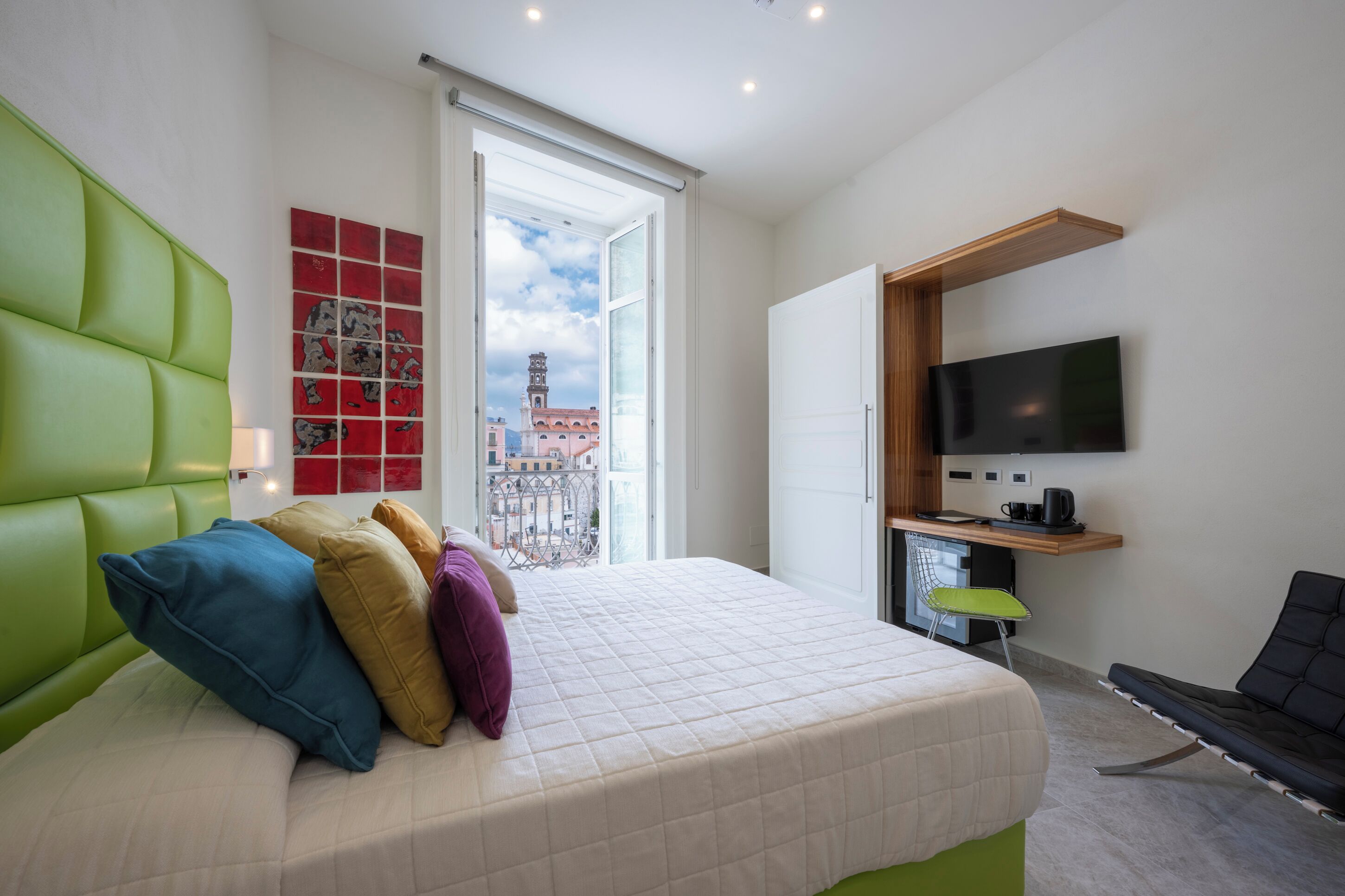 A hotel room with a bed, a TV, a desk, and a chair.